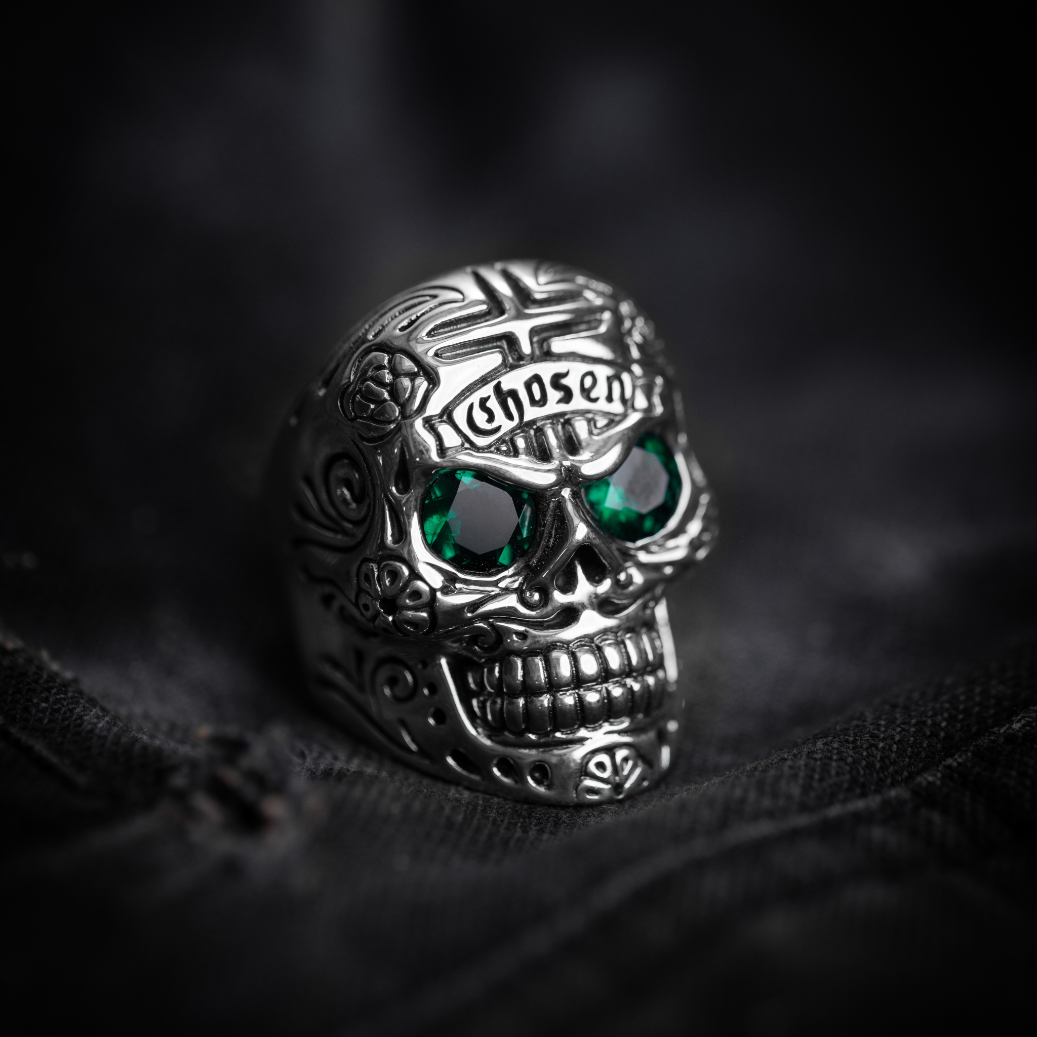 Large Skull Ring with Chosen Cross Detail and Green Emerald Eyes glamour shot on black denim