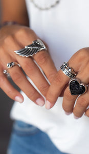 Close up shot of woman's hands with wing ring, black heart ring, skull ring and star ring.