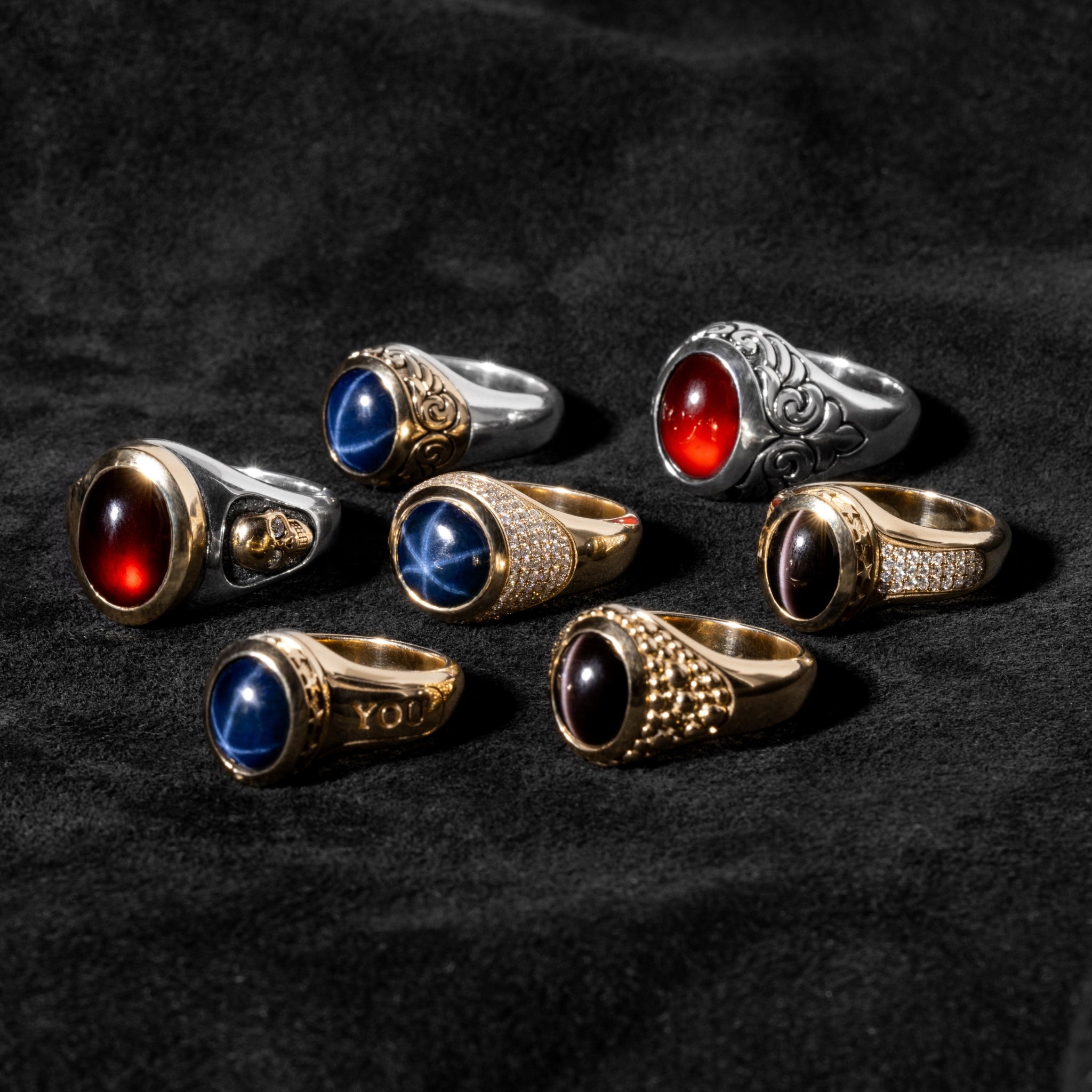 Assorted silver and gold signet rings on black fabric