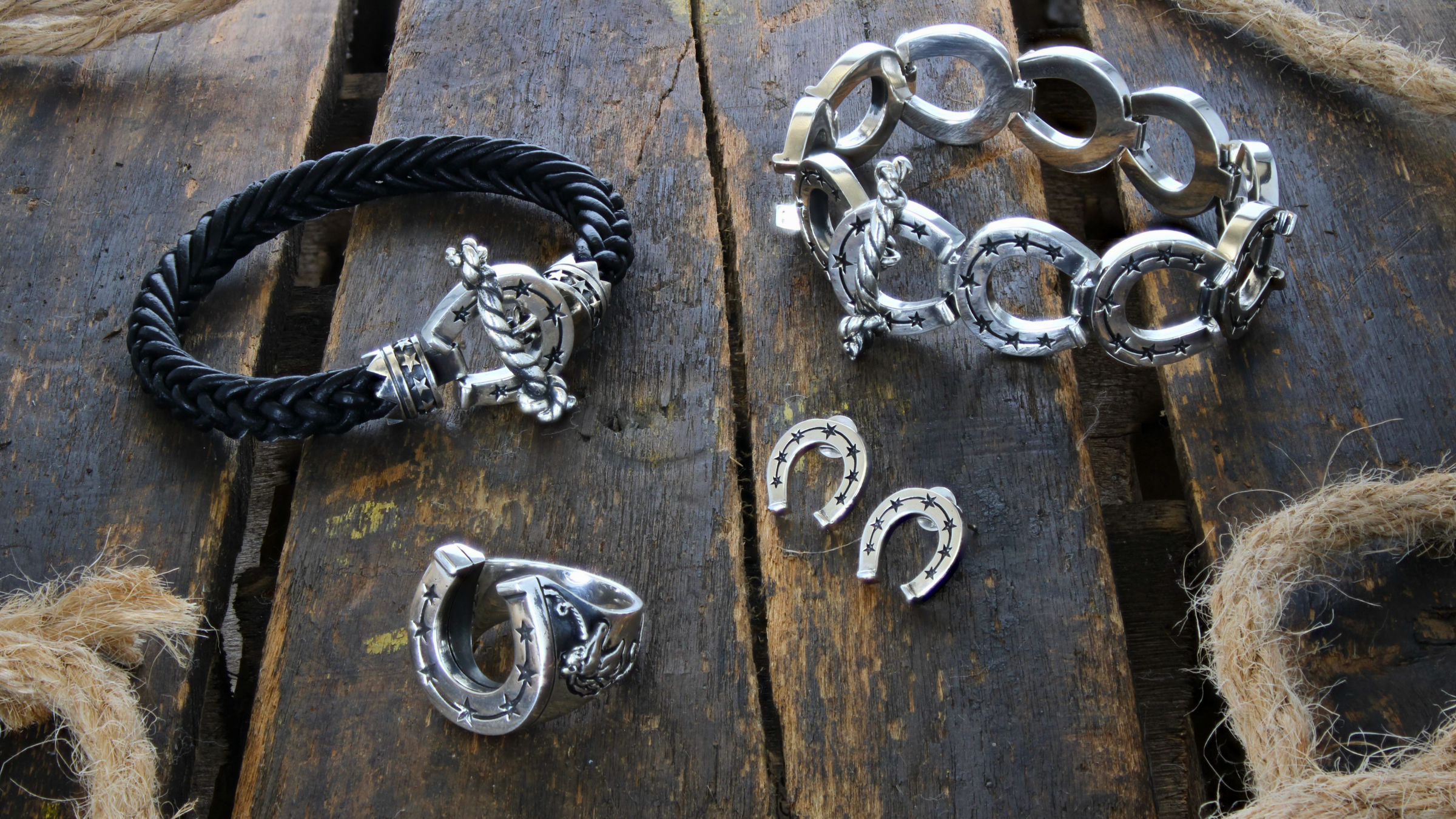 Silver jewelry including bracelets and rings on a wooden surface