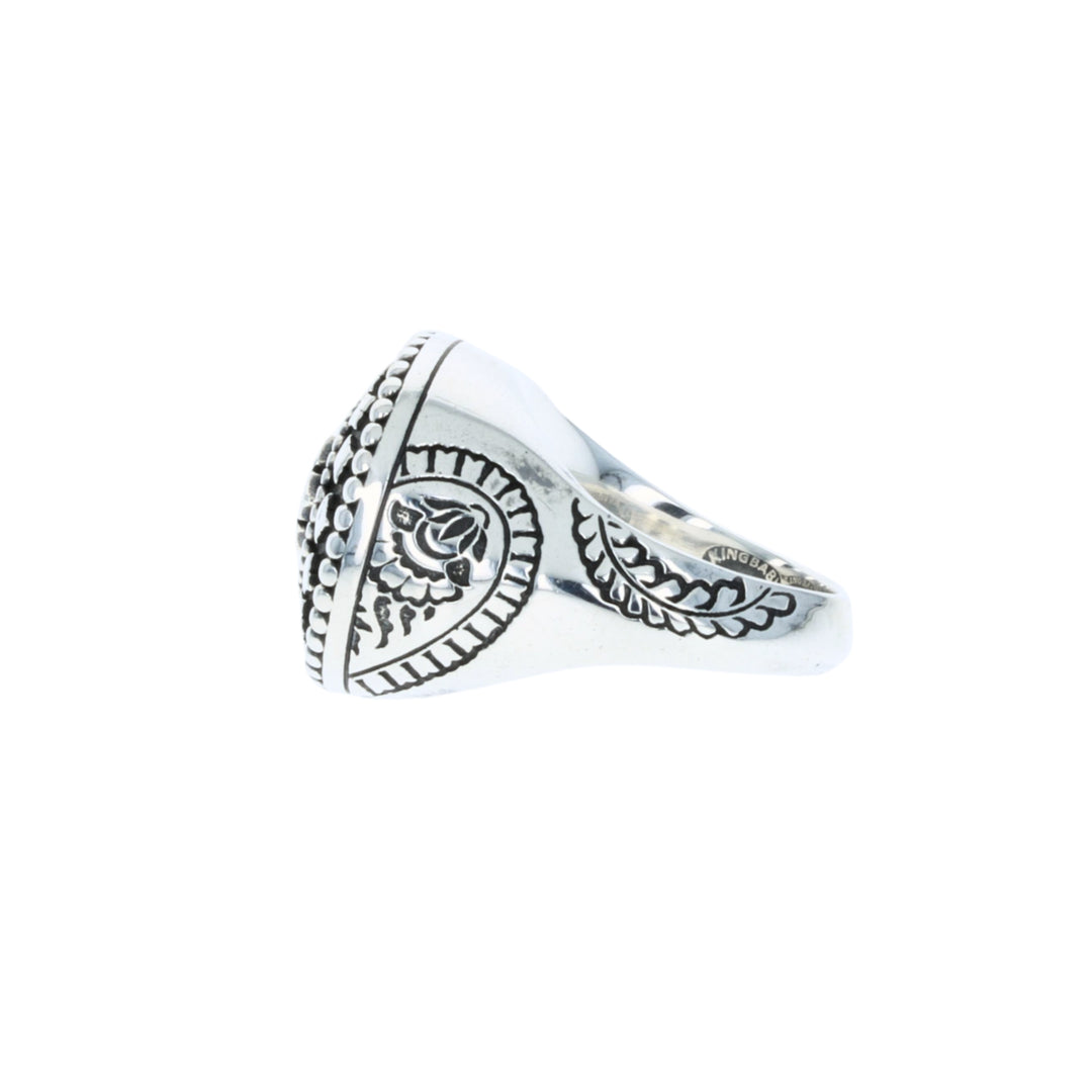 Silver ring with intricate design on a white background