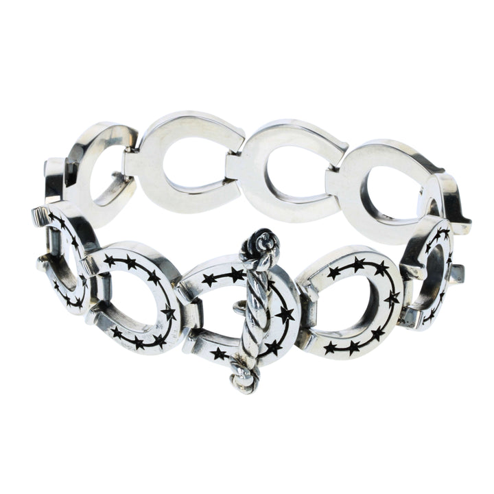 Silver bracelet with horseshoe star designs on a white background