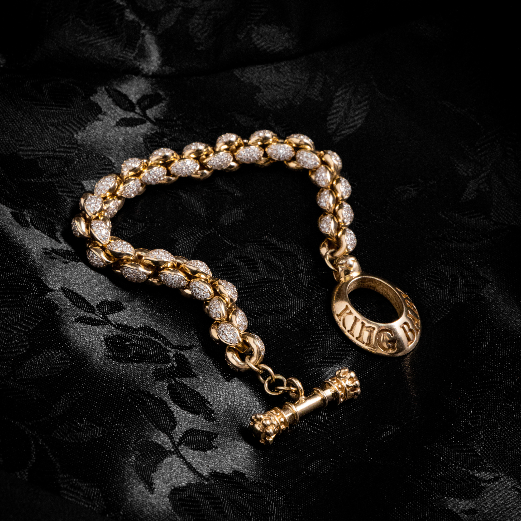 Slightly Lit Shot of 10k Gold Large Infinity Link Bracelet w/ Pave Diamonds on black background