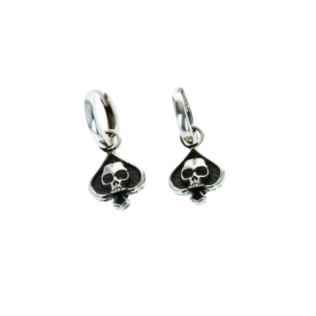 Pair of silver earrings with skull and spade design on a white background