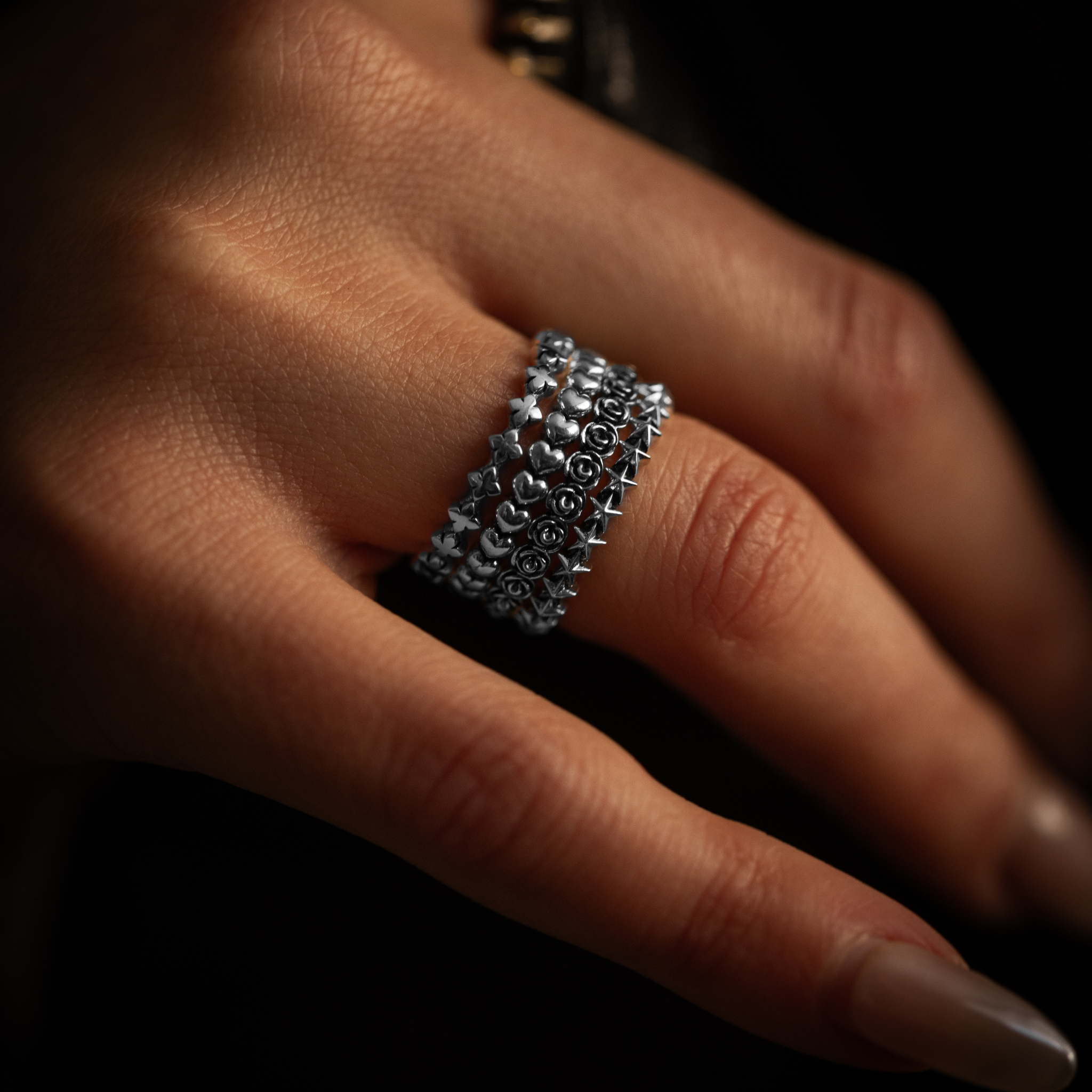 all styles of micro stackable rings - mb cross, heart, rose and star - stacked on finger