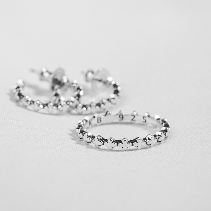 micro stackable mb cross silver ring in front of earrings