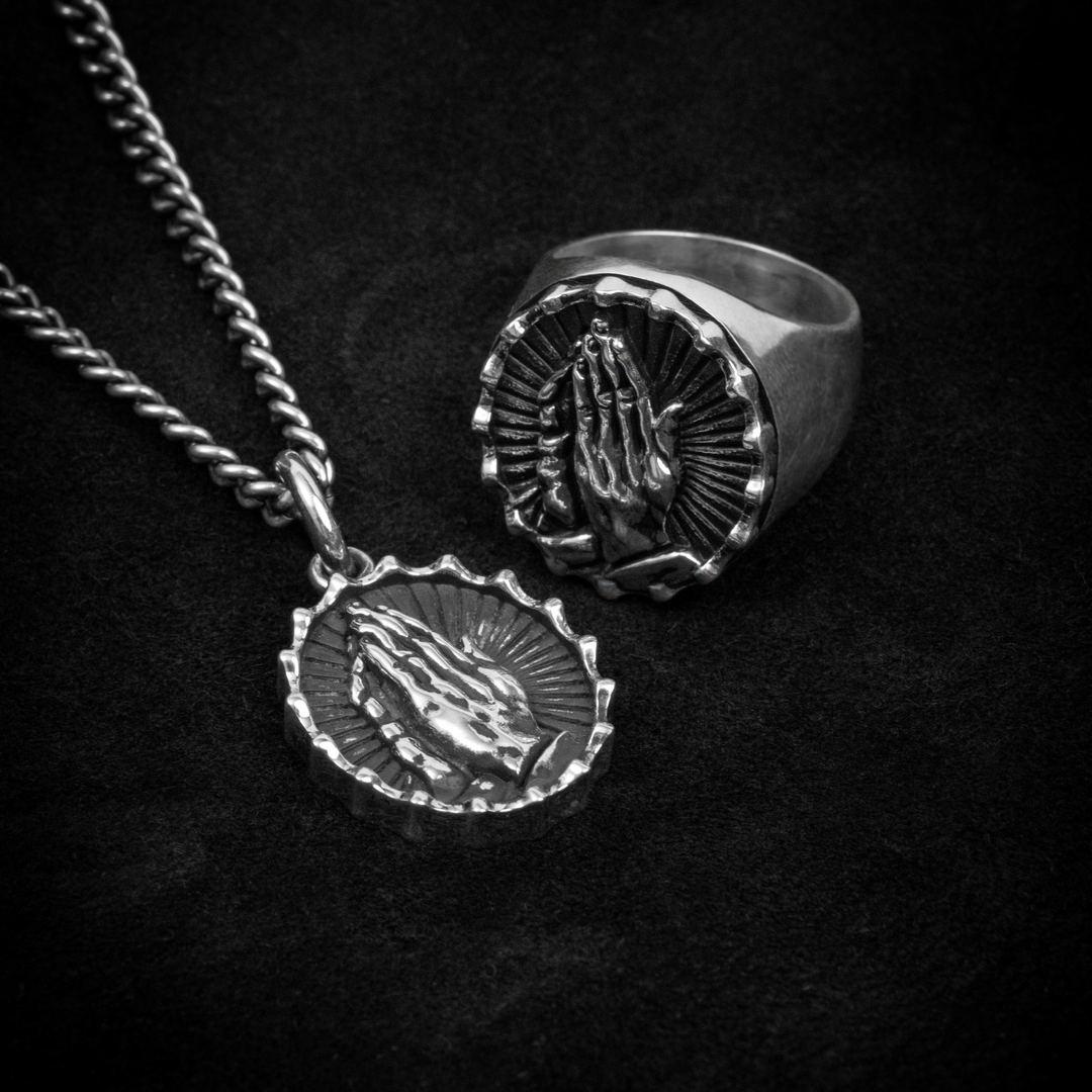 Praying hands pendant and ring on black background