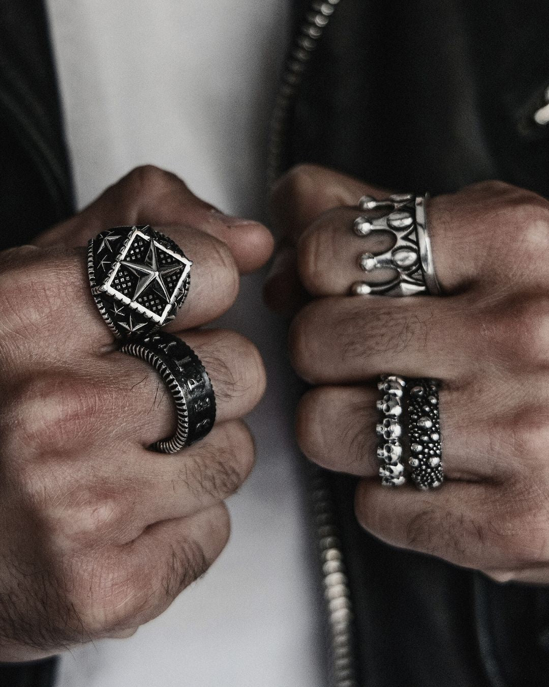 Close-up of hands wearing multiple silver rings with intricate designs.