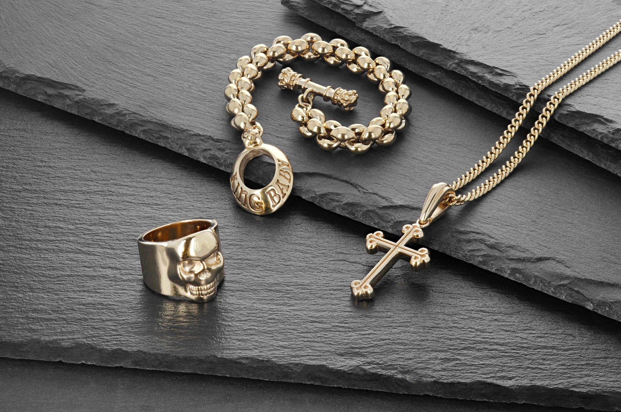 Lifestyle shot of 10K Gold Small Classic Skull Ring, 10K traditional cross, 10k fine curb chain, 10k large infinity link bracelet