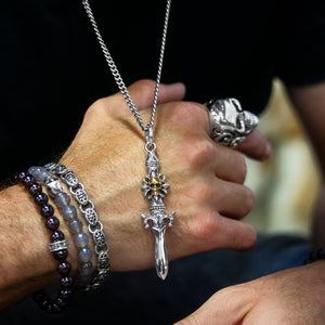 man wearing sterling silver jewelry, beaded bracelets, dagger pendant, and skull ring
